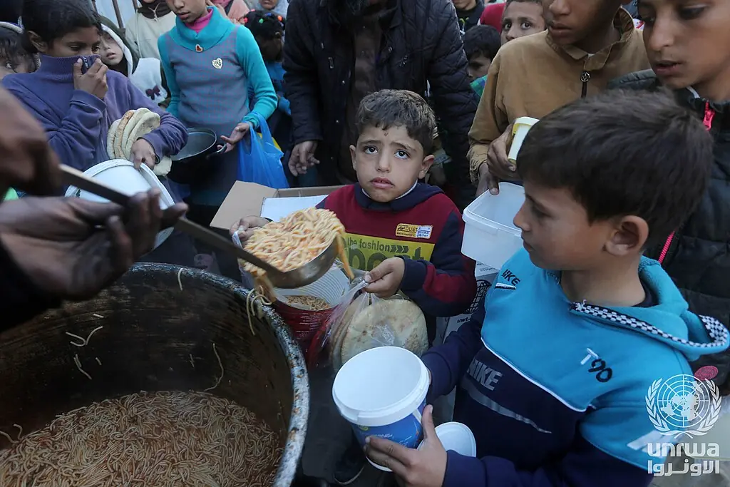 File photo: displaced Palestinians receive food from a charity kitchen in Deir el-Balah, Gaza Strip, March 2025.